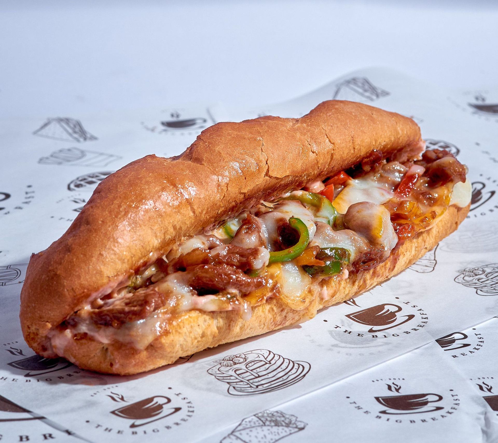 Close-up of a Philly cheesesteak sandwich with melted cheese and grilled vegetables, perfect for food lovers.